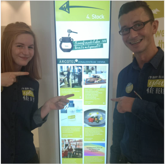 two people pointing at a social wall display.