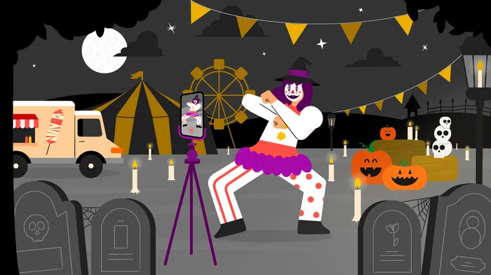 A clown filming themselves with a smartphone at a circus surrounded by pumpkins, skulls and gravestones.