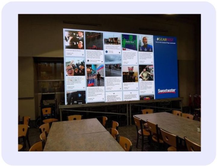 Large venue screen displaying an audience activation platform showing a live social media wall with photo and text posts alongside Sweetwater #GEARFEST branding.