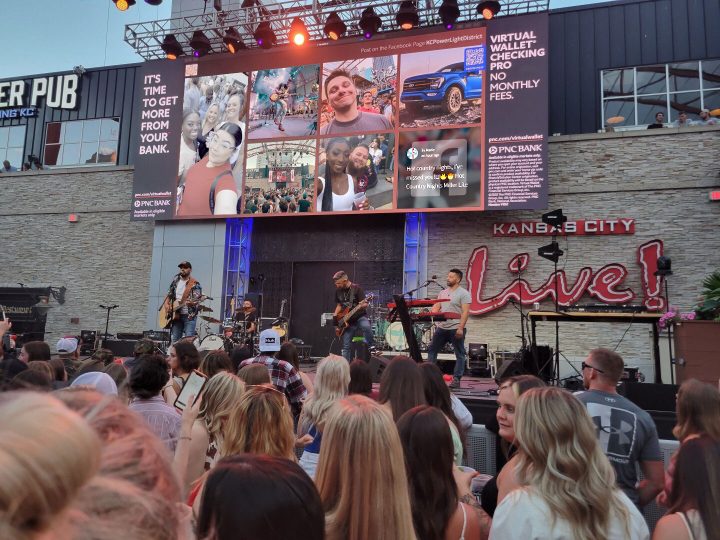 A concert with many attendees looking up at a social media event display.